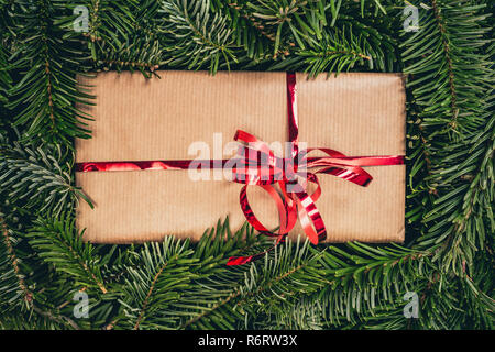 Weihnachten Geschenk auf grünen Kiefer Fichte oder. Vintage rot glänzend Band auf einem Papier Geschenkbox. Top Detailansicht mit kopieren. Stockfoto
