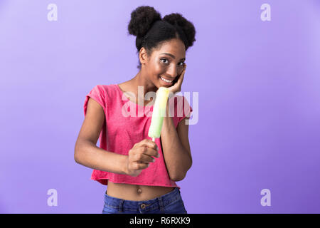 Foto der jungen afrikanische amerikanische Frau und lächelnd Eis über violett Hintergrund isoliert Stockfoto