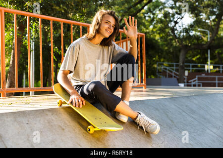 Foto von jugendlich Kerl 16-18 in Freizeitkleidung auf Rampe mit Skateboard, Skate Park während der sonnigen Sommertag Stockfoto