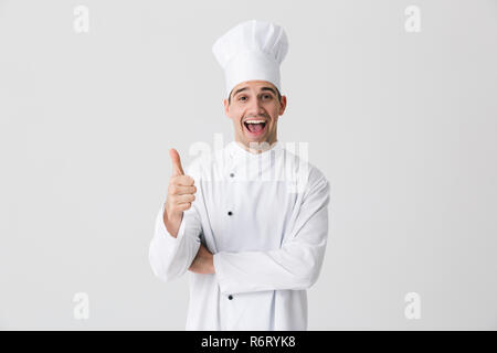 Bild von gutaussehenden jungen Mann aufgeregt, Küchenchef im Innen Isoliert über weiße Wand im Hintergrund mit Daumen nach oben Geste. Stockfoto