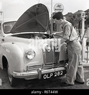 1950, historische, ein Austin Auto mit seiner Motorhaube bis an den Zapfsäulen zu einem Mobilgas Service Station geparkt, ein junger Service attendant Befüllen Kühler des Autos mit Wasser, England, UK. Stockfoto