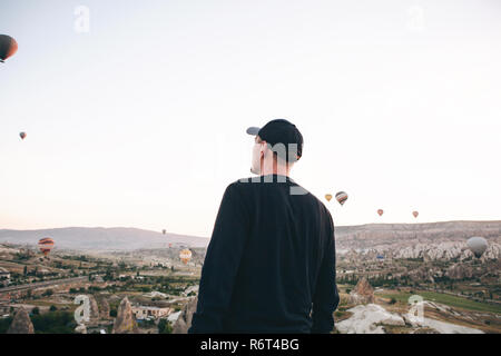 Ein Mann, der in der Einsamkeit bewundert einen schönen Blick auf das fliegende Ballons in Kappadokien in der Türkei. Stockfoto