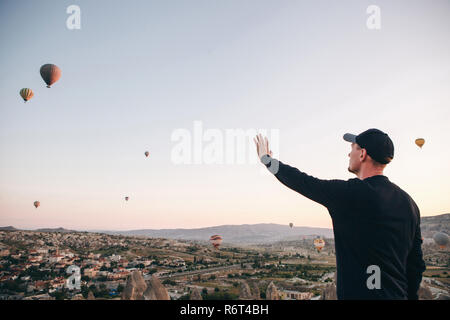 Ein Mann, der in der Einsamkeit bewundert einen schönen Blick auf das fliegende Ballons in Kappadokien in der Türkei. Stockfoto