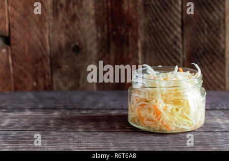 Glas Glas mit Sauerkraut steht auf dunklem Hintergrund. Stockfoto