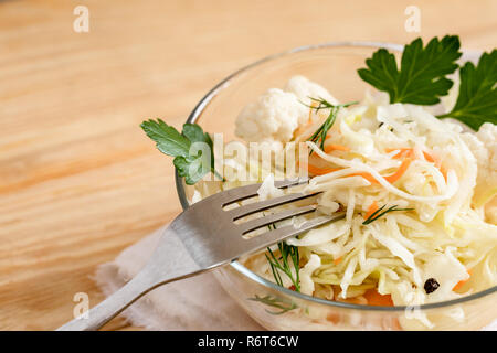 Close-up Sauerkraut und Gabel in Glasschüssel steht auf hellem Holz Tisch. Stockfoto