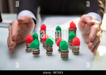 Unternehmer schützen Haus Modelle auf Gestapelte Münzen Stockfoto