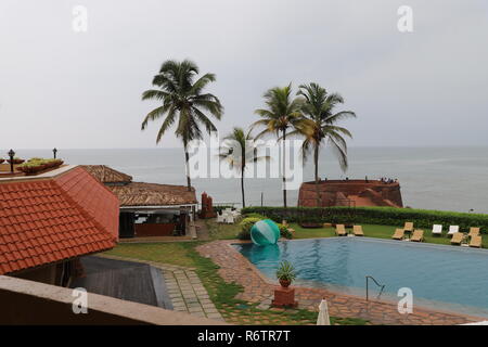 Beruhigenden Blick von einem Fort Resort in North Goa, bestehend aus einem Pool, exotische Resort Hütten, Kokospalmen und die nie endende Meer Stockfoto