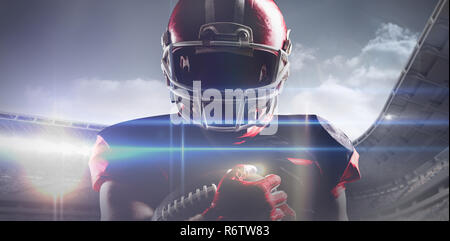 American football player im Helm Holding rugby ball gegen das zusammengesetzte Bild des Sports Arena Stockfoto