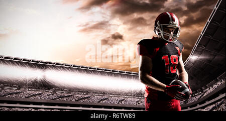 American football player im Helm Holding rugby ball gegen das zusammengesetzte Bild im Stadion mit bewölktem Himmel Stockfoto