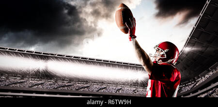 American Football Spieler mit Helm und Rugby Ball gegen das zusammengesetzte Bild des Sports Arena mit Anhänger Stockfoto