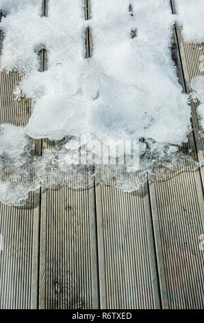 Schmelzender Schnee auf einer hölzernen Terrasse, close-up Stockfoto