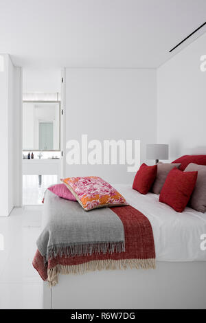 Rot- und gedämpften Rosa Kissen auf Doppelbett mit Einbauschrank im minimalistischen Schlafzimmer der Villa bauen, Quinta do Lago Stockfoto