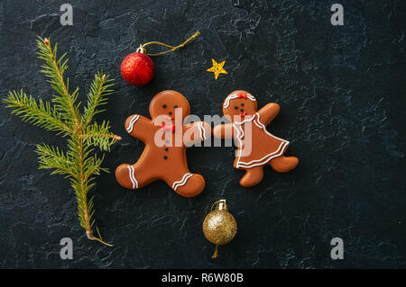 Weihnachten Hintergrund. Gingerbread Man und Mädchen cookies, Tannenbaum, Bälle auf einem schwarzen Stein. Ansicht von oben. Stockfoto