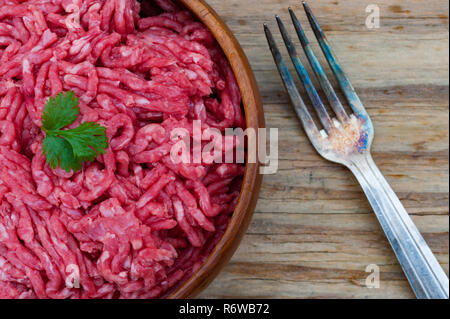 Schale der rohen Hackfleisch Fleisch, Metall Gabel auf hölzernen Tisch Hintergrund Stockfoto