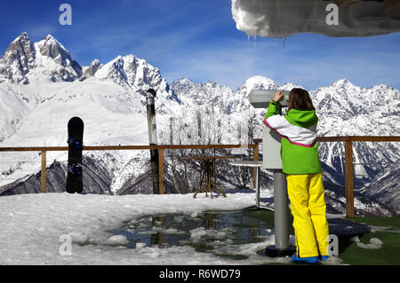 Mädchen schaut durchs Fernglas auf der Aussichtsplattform des Skigebiet im Winter Berg an sonnigen Tag. Kaukasus Berge. Hatsvali, Swaneti Region von Georg Stockfoto