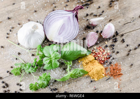 Food-fotografie. Mahlzeit Zutaten - rote Zwiebel, Knoblauch, schwarzer Pfeffer, frisch geschnittene Basilikumblätter und bunten Gewürzen auf Holztisch. Flachbild layout Bild. Stockfoto