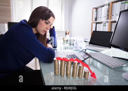Roter Pfeil über Abnehmende gestapelte Münzen Stockfoto