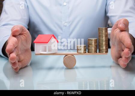 Schutz der Balance zwischen Haus Modell und gestapelte Münzen Stockfoto