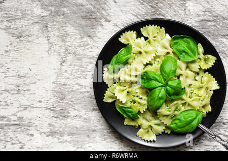 Farfalle Nudeln mit Basilikum Pesto und Kräutern in einen Teller. top View Stockfoto