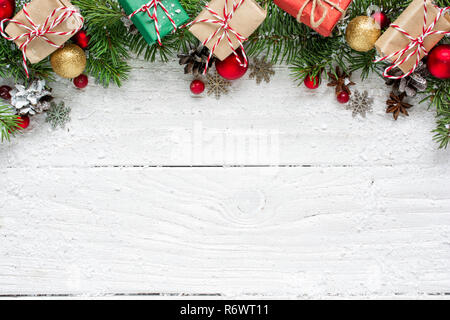 Weihnachten Hintergrund mit Tannenzweigen, Dekorationen, Geschenkverpackungen und Tannenzapfen auf weissem Holztisch. Weihnachten Hintergrund. Flach. Ansicht von oben mit Co Stockfoto