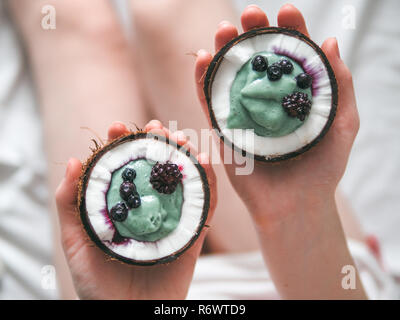 Zwei coconut Hälfte spirulina Smoothie in Frau Hände Stockfoto