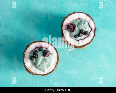 Zwei coconut Hälfte spirulina Smoothie auf blauen Tabelle Stockfoto