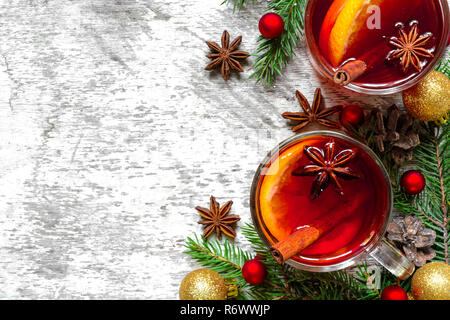 Glas Glühwein mit Zimt, Anis und Tannenbaum Äste mit Dekorationen auf weißem Holz- Hintergrund mit Kopie Raum. top anzeigen. winter Christus Stockfoto