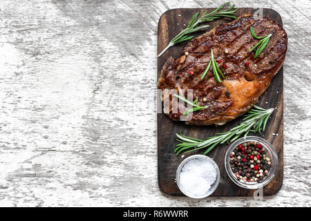 Gegrilltes Rindersteak mit Kräutern und Gewürzen auf Holz Schneidebrett. Ansicht von oben mit der Kopie Raum Stockfoto