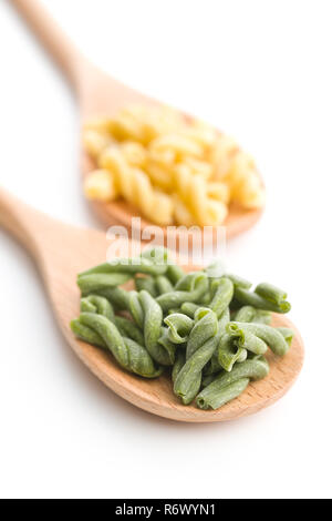 Nicht gegartem Spinat gemelli Pasta in hölzernen Löffel auf weißem Hintergrund. Stockfoto