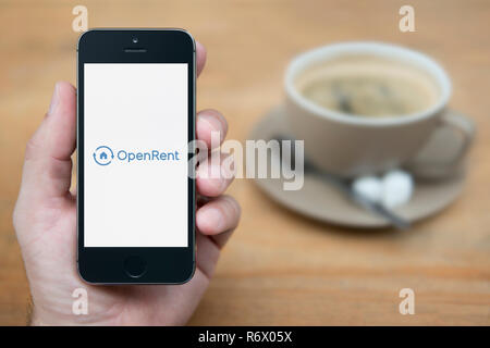 Ein Mann schaut auf seinem iPhone die zeigt die OpenRent Logo (nur redaktionelle Nutzung).