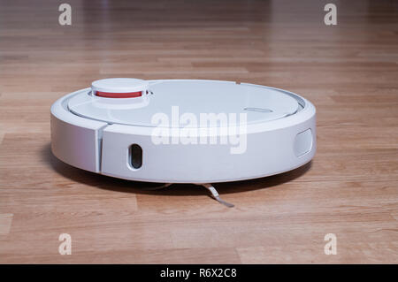Weiße Roboter Staubsauger auf Parkettboden Reinigung Staub im Zimmer. intelligente Roboter automatisieren wireless Reinigungstechnik und Sauberkeit. Stockfoto