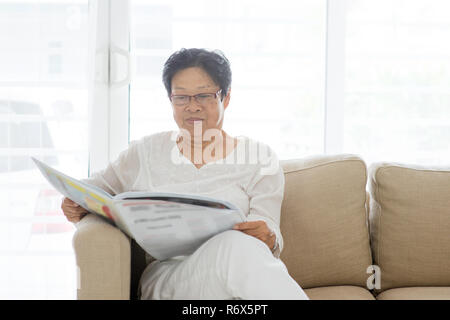 Asiatin senior lesen Zeitung Stockfoto
