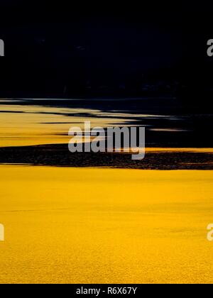 Fast goldene Farbe hell gegen die untergehende Sonne Reflexion auf der Oberfläche des Meeres Stockfoto