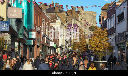 WINDSOR, ENGLAND - NOVEMBER 2018: Straße in Windsor Innenstadt mit Weihnachtskäufer überfüllt. Schloss Windsor ist im Hintergrund. Stockfoto