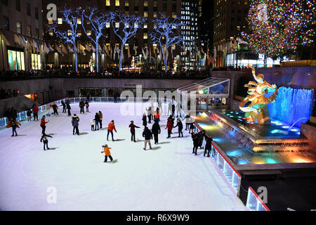 NEW YORK - Dezember 4, 2018: eine hell erleuchtete Rockefeller Plaza mit einem Weihnachtsbaum. Die Eisbahn, gefüllt mit Touristen Schlittschuhlaufen auf Deze Stockfoto