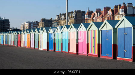 Eine Zeile mit 25 bunten Badekabinen am Brighton Promenade mit einem abnehmenden Perspektive, die Sonne scheint mit einem blauen Himmel. Stockfoto