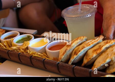 Lecker gebackene empanadas Tablett serviert mit Nachos und verschiedenen Saucen. Stockfoto