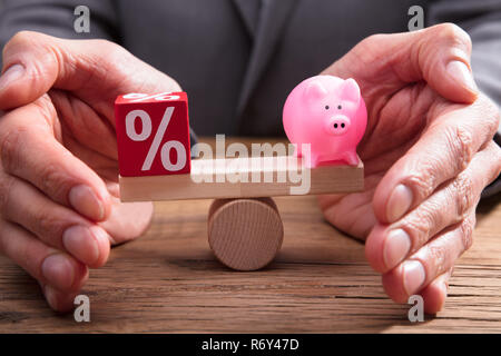 Die schützende Hand Balance zwischen Prozentsatz und Sparschwein Stockfoto