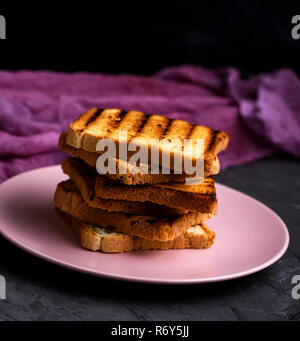 Stapel von Square getoasteten Brotscheiben in einem rosa Keramikplatte liegen Stockfoto