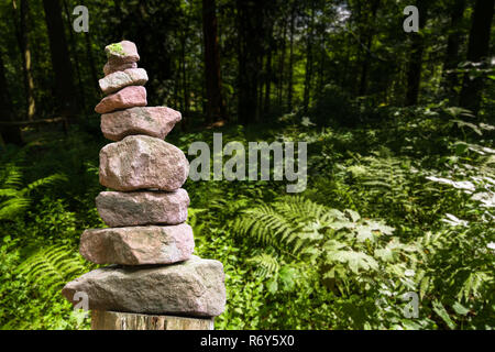 Gestapelte Stein Pyramide vor einer Wiese mit Farnen Stockfoto