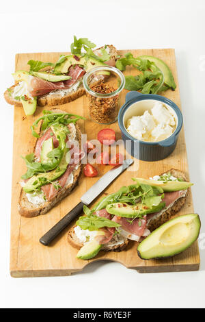 Rustikale Zwiebel Brot mit Frischkäse, Parma Schinken, Avocado, Rucola, Thymian, Chili, Quark und Tomate, Studio Stockfoto