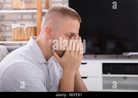 Seitenansicht eines umgekippten Junge Mann sitzt auf einem Sofa Stockfoto