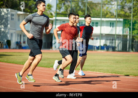 Vier jungen asiatischen Leichtathleten racing gegeneinander konkurrieren. Stockfoto