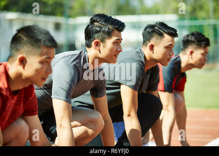 Jungen asiatischen Leichtathleten sprinter Einstellung am Start. Stockfoto