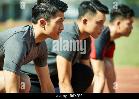 Jungen asiatischen Leichtathleten sprinter Einstellung am Start. Stockfoto