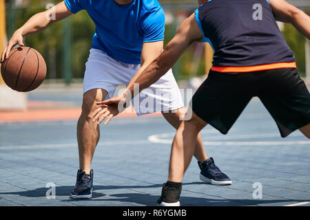 Jungen asiatischen Erwachsene Basketball spielen unter der Sonne im Freien. Stockfoto