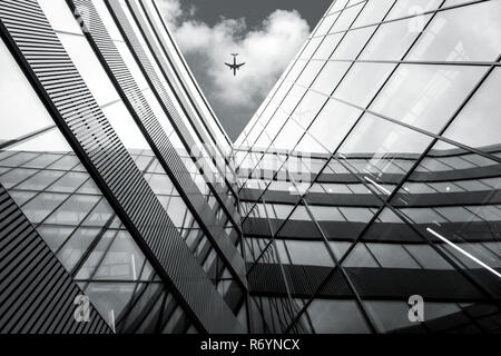 Low Angle View von fliegenden Flugzeug über moderne Architektur Gebäude Stockfoto