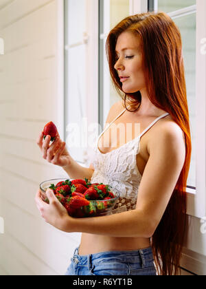 Schöne Rothaarige mit Schüssel Erdbeeren Stockfoto