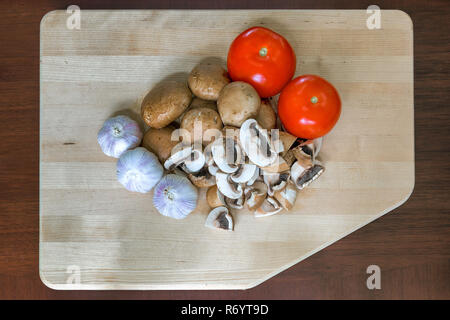Tomaten, Knoblauch und der Portobello Pilz auf Schneidebrett Stockfoto
