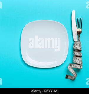 Messer mit einer Gabel in ein Maßband mit einer weißen Keramikplatte gewickelt Stockfoto